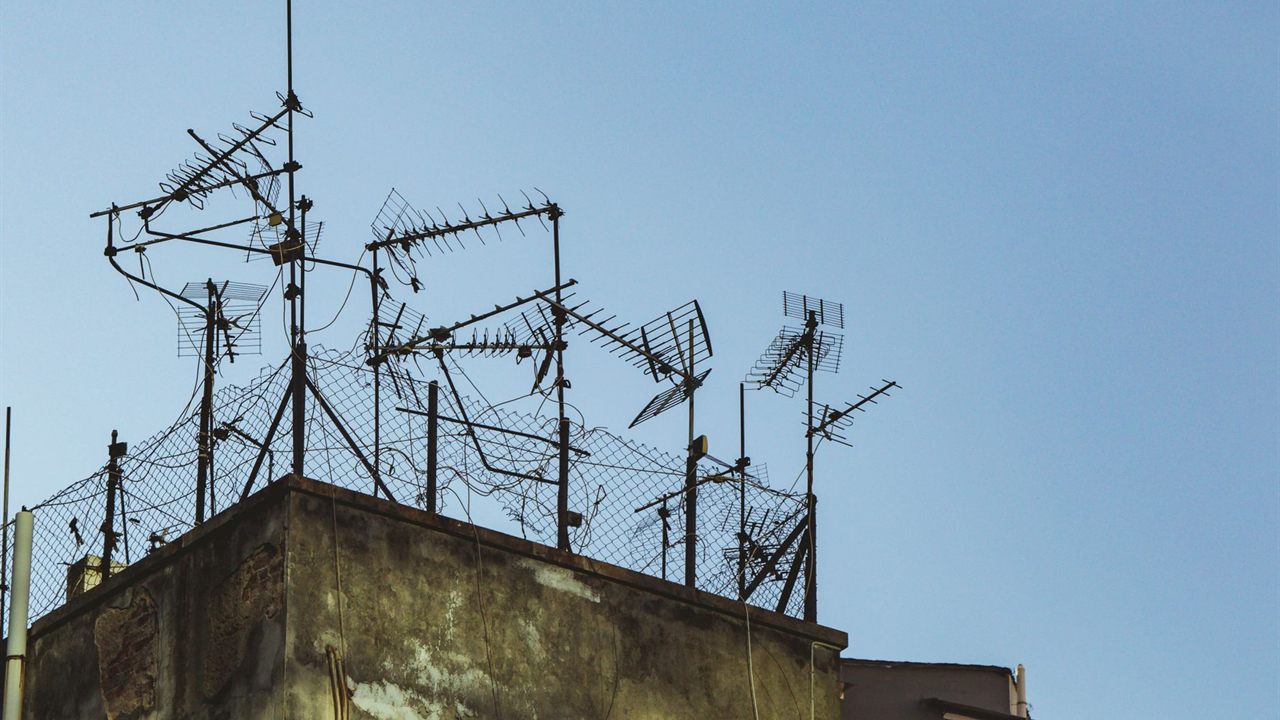Cluster of TV antennas on masts and braced frames above a flat rooftop