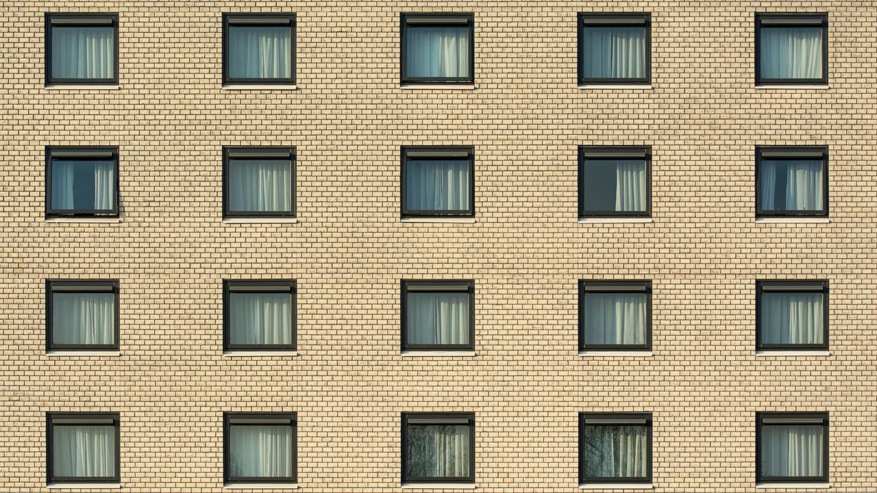 Brick apartment facade with rows of windows, the walls an indoor TV antenna has to receive through