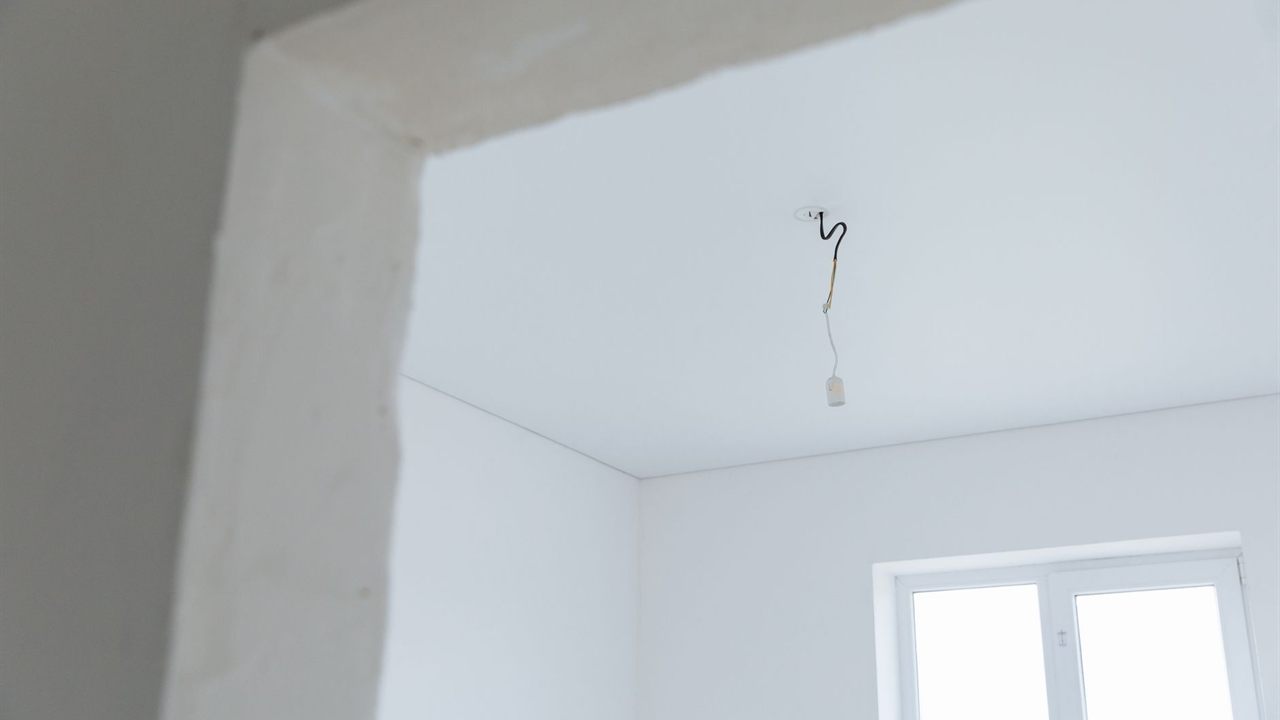 Bare white ceiling near a corner with a cable dropped through it at rough-in