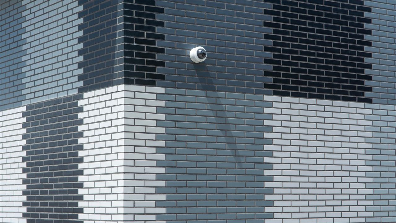 Dome security camera on an exterior brick wall at the end of an outdoor cable run
