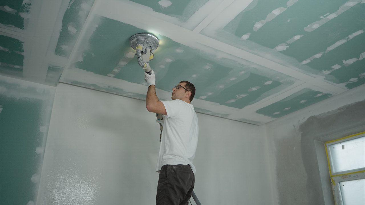 Installer finishing a drywall ceiling before speaker cut-outs are made