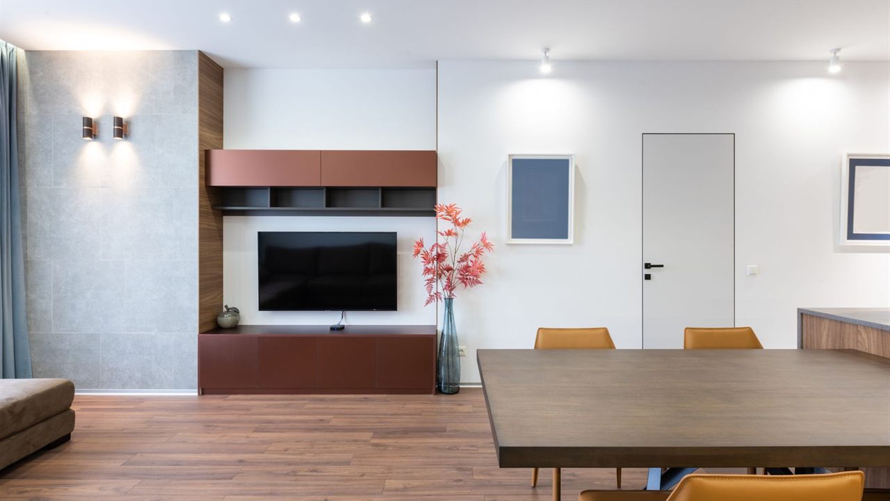 Flat TV hung low and flush on a white wall above a media cabinet