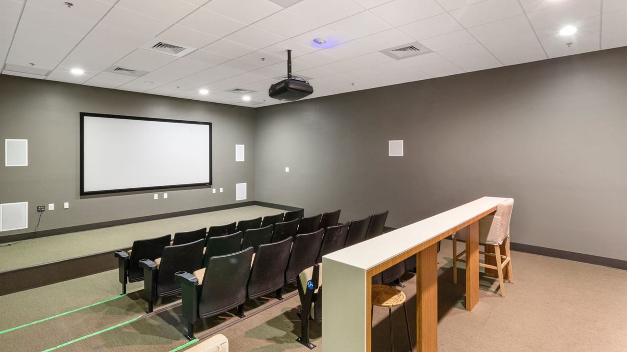 Theater room with a blank projection screen, ceiling projector and seating