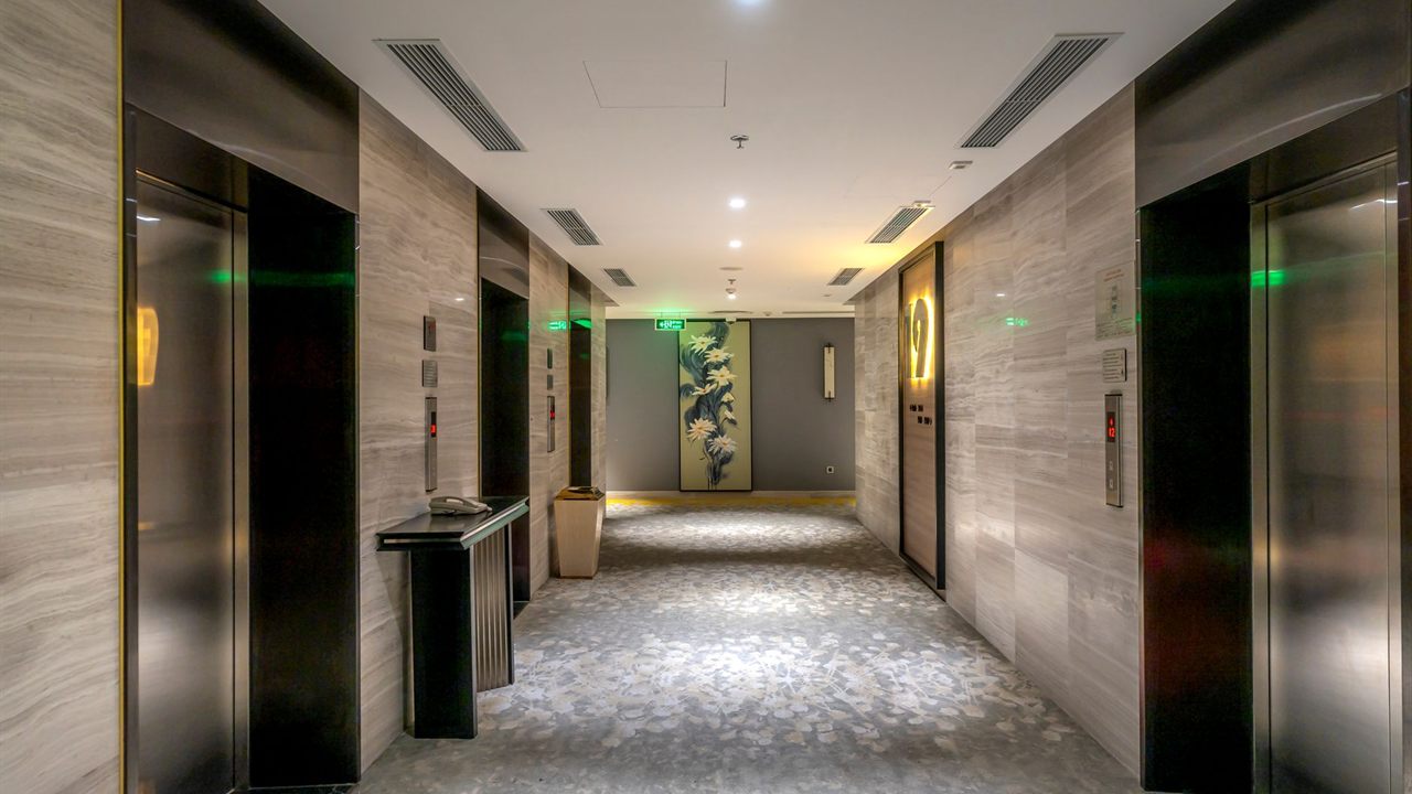Hotel elevator lobby with a long finished ceiling to cover with sound