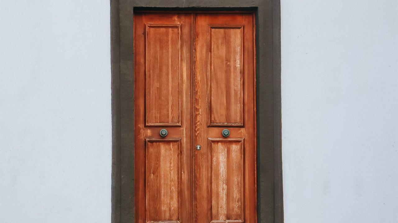 Closed wooden double front door set in a plain plastered wall