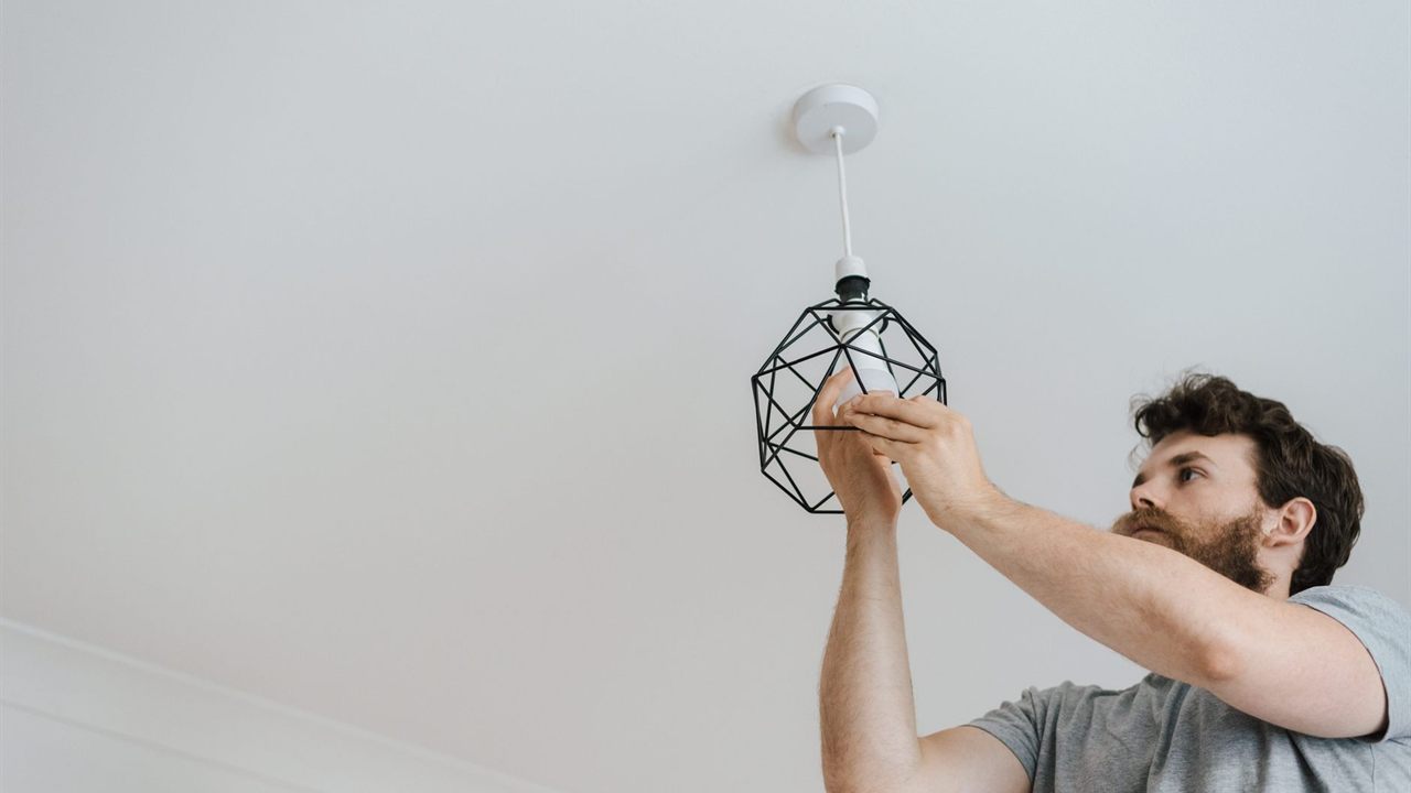 Installer reaching up to work on a white ceiling fixture
