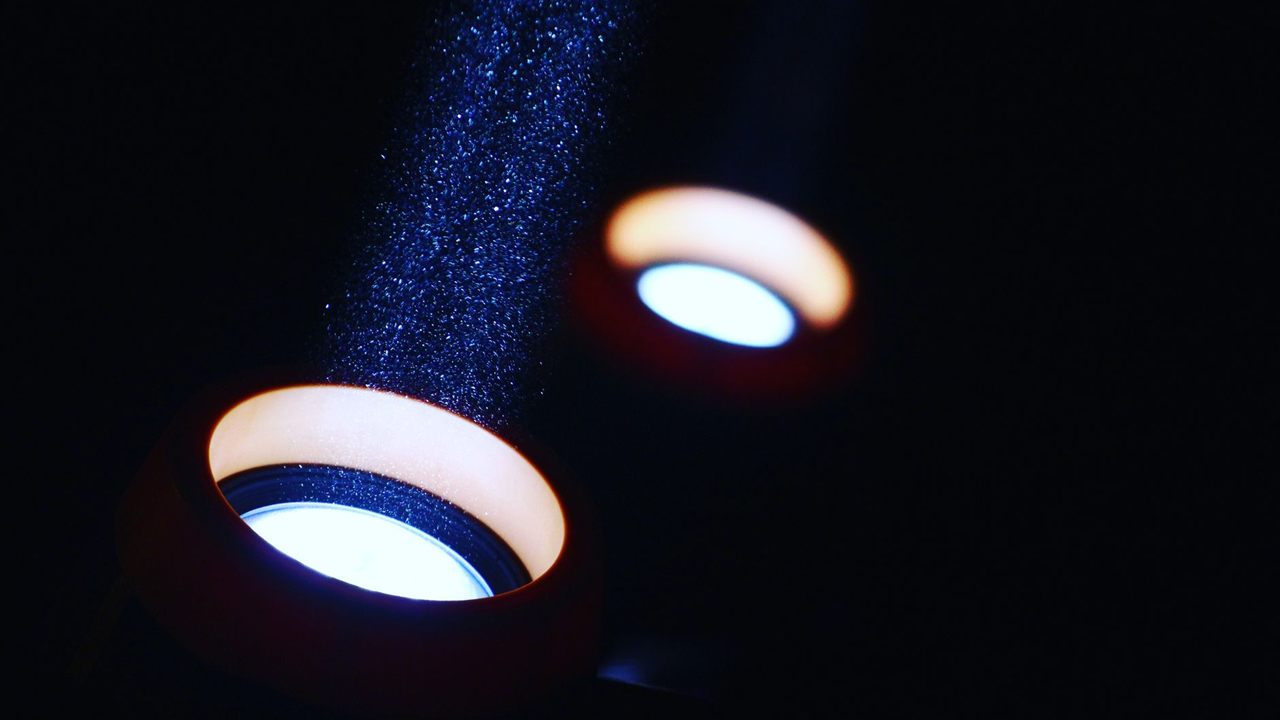 Two lights casting beams through dusty air in a dark room