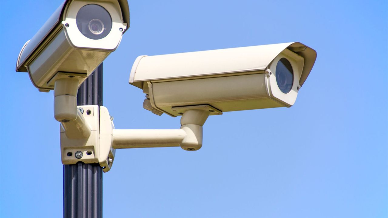 Two outdoor box cameras in housings on a pole, a long cable run to plan power for