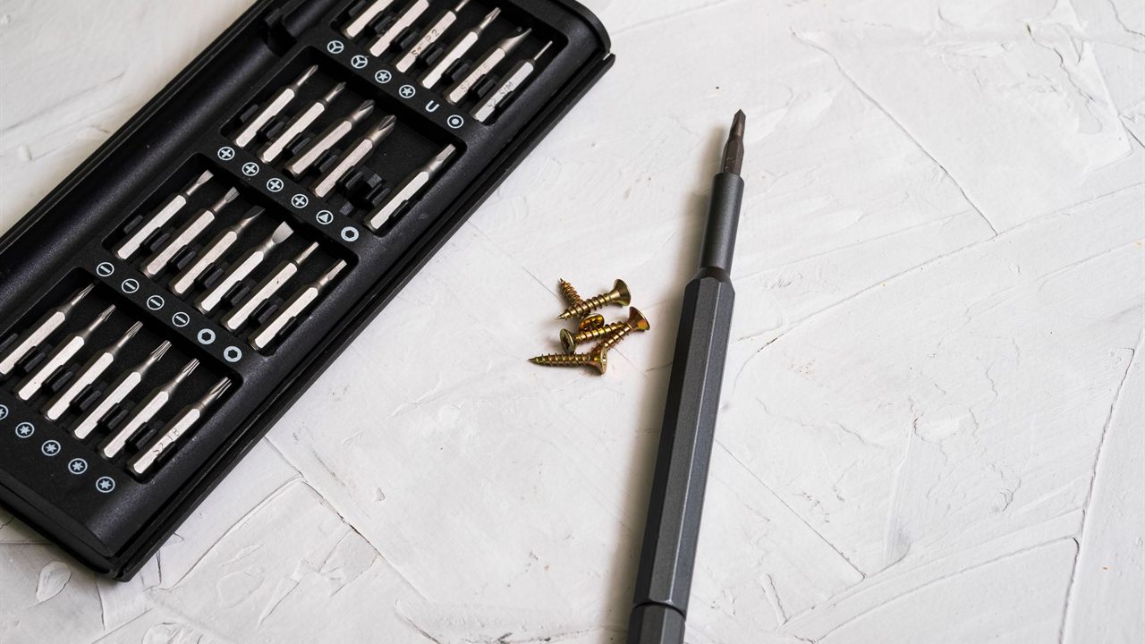 Precision screwdriver, bit set and screws laid out for a device install