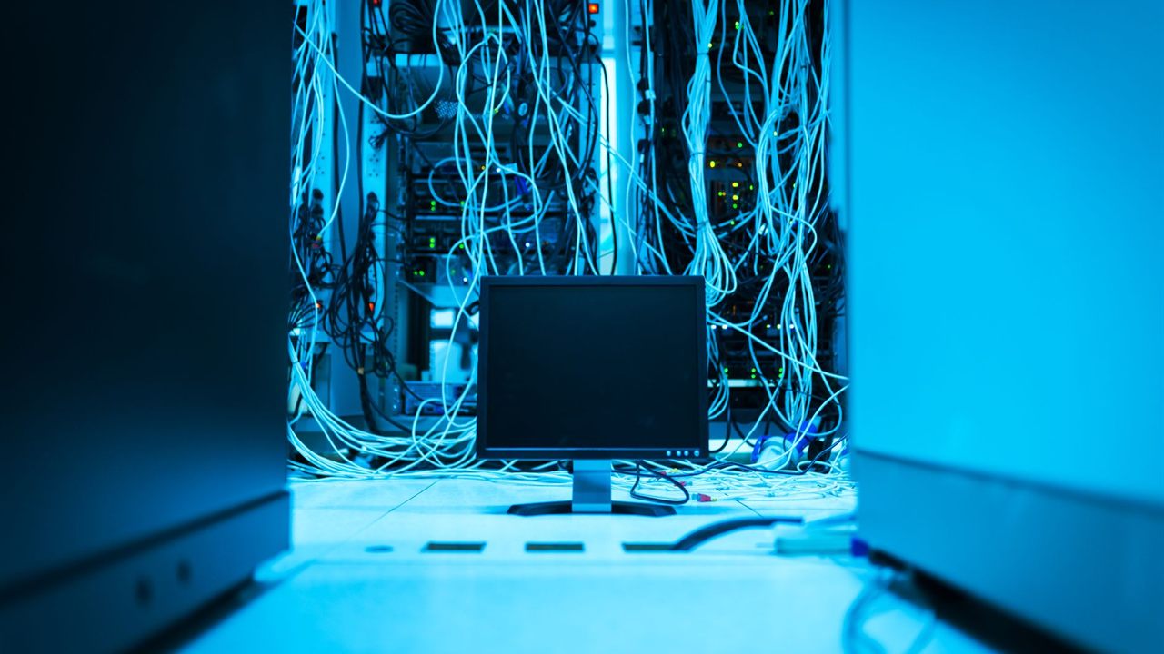 Network cables hanging behind equipment racks in a server room, where PoE switches are installed