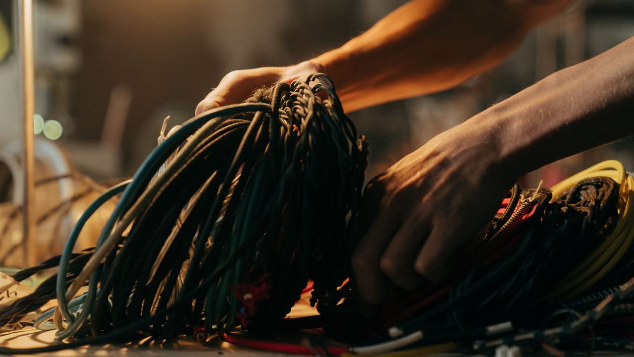 Hands sorting thin colored conductors on a workbench before a prewire
