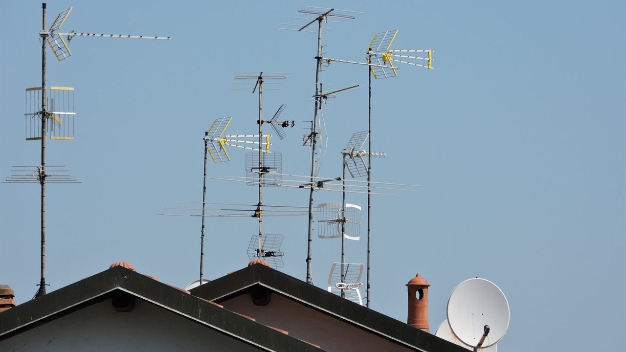 Several TV antennas on tall masts above a pitched tile roof