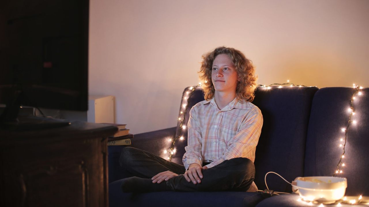 Viewer on a couch facing a TV in a dimly lit living room