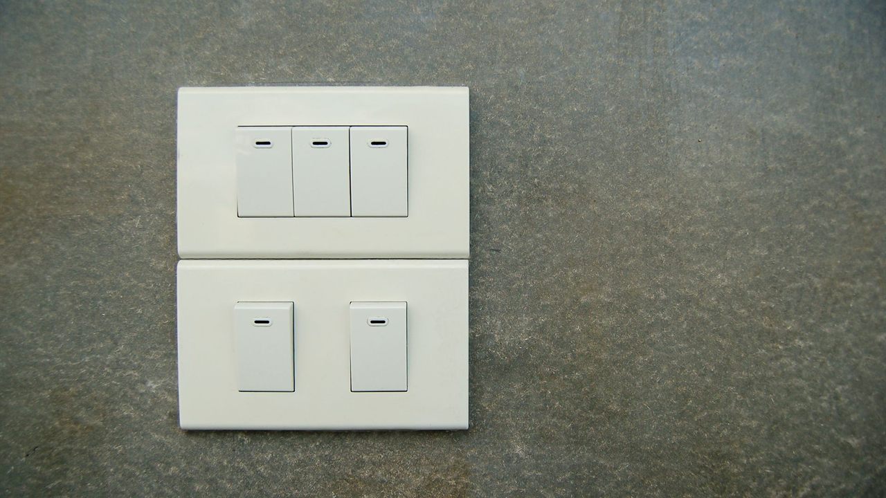 White multi-gang wall light switches on a grey wall
