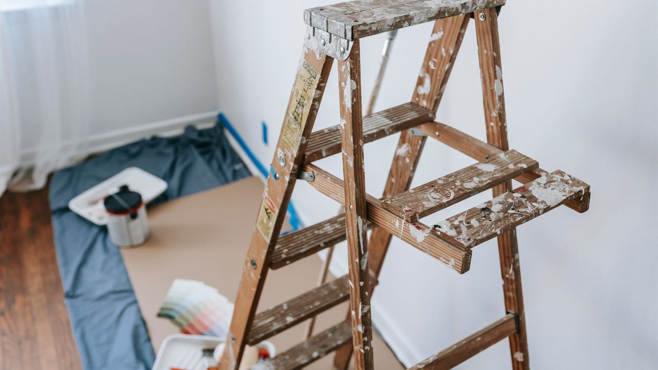 Paint-spattered wooden stepladder set up in a room for overhead work
